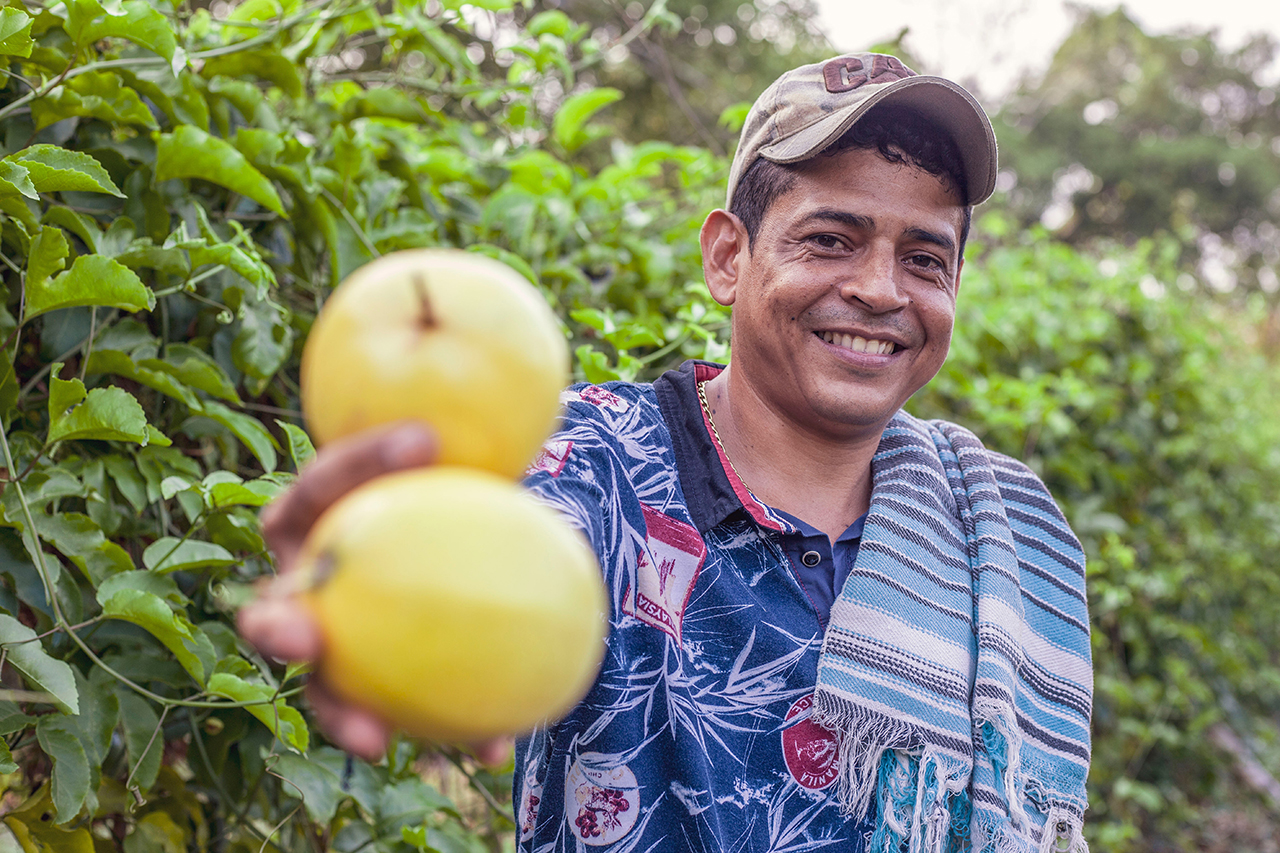 Hombre sosteniendo dos frutas y mirando con sonrisa